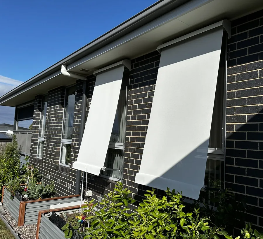Straight drop awnings lowered over windows on a dark brick home