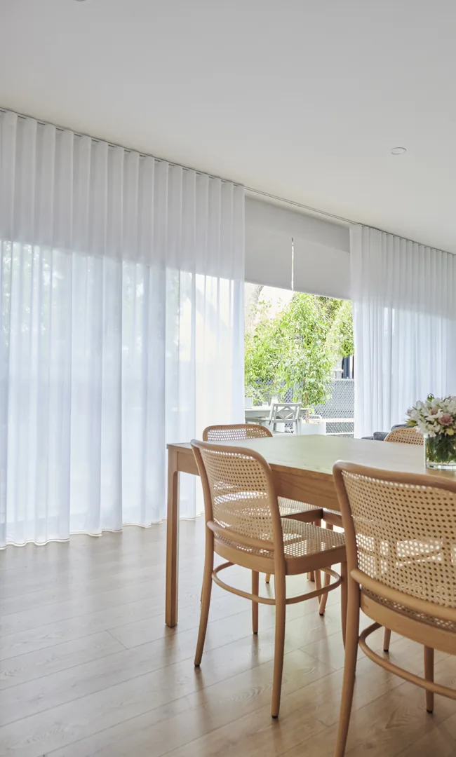 Sheer curtains drawn across a dining room window wall