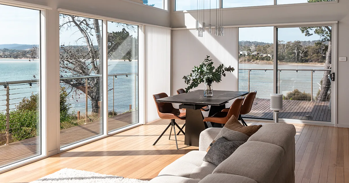 Honeycomb blinds raised across a coastal living room at Dodges Ferry, with the water beyond